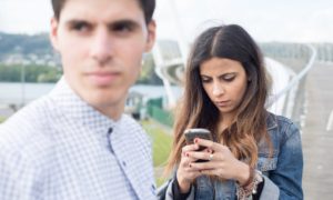 Una ragazza concentrata nello smartphone e un ragazzo trascurato che sperimenta phubbing